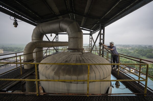 A technician works on the top deck of a distillery at Bajaj Hindustan Sugar factory that produces ethanol, a type of biofuel, in Meerut, India, Wednesday, Aug. 23, 2023. (AP Photo/Altaf Qadri)