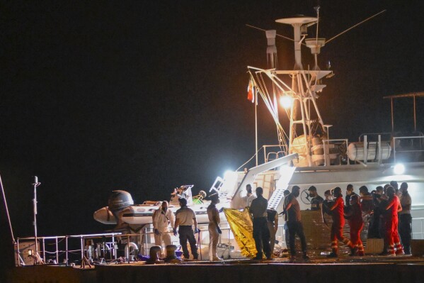 The bodies of some of the 64 migrants missing in the Mediterranean Sea after their ship wrecked off Italy's southern coast are disembarked at the Italian southern port-city of Roccella Ionica, early Wednesday, June 19, 2024. U.N. agencies said the boat that wrecked off Calabria had set off from Turkey eight days earlier and caught fire and overturned. Eleven people were rescued Monday, but one died soon after they were brought to land. (AP Photo/Valeria Ferraro)