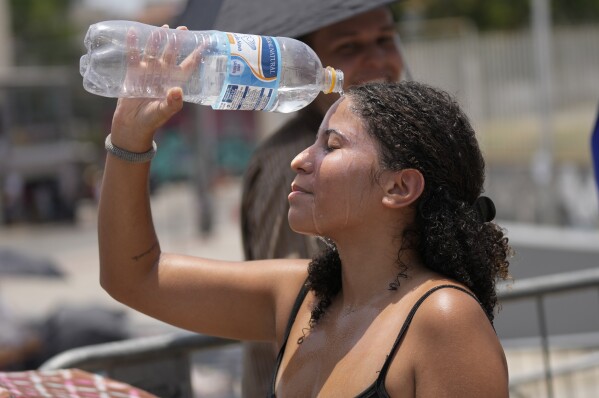Taylor Swift fan cools off with a bottle of water amid a heat wave before The Eras Tour concert outside Nilton Santos Olympic stadium in Rio de Janeiro, Brazil, Saturday, Nov. 18, 2023. (AP Photo/Silvia Izquierdo)