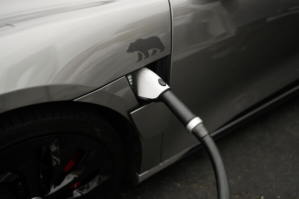 FILE - A Combined Charging System (CCS) connector is plugged into an electric vehicle at a charging station, June 9, 2023, in Anaheim, Calif. On Thursday, Dec. 21, Maine environmental regulators are set to decide whether the state should join others that have adopted California-style regulations that drastically limit the sale of new gas-powered vehicles. (AP Photo/Jae C. Hong, File)