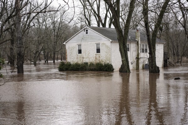 A home is surrounded by floodwaters from the Perkiomen Creek in Collegeville, Pa., Monday, Dec. 18, 2023. (AP Photo/Matt Rourke)