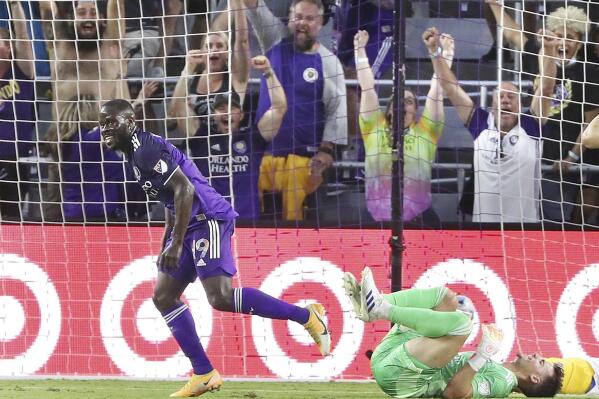 Orlando player Benji Michel celebrates in front of fans and fallen San Jose goalkeeper J.T. Marcinkowski, right, after scoring a goal during a MSL soccer match in Orlando, Fla., on Tuesday, June 22, 2021. (Stephen M. Dowell /Orlando Sentinel via AP)
