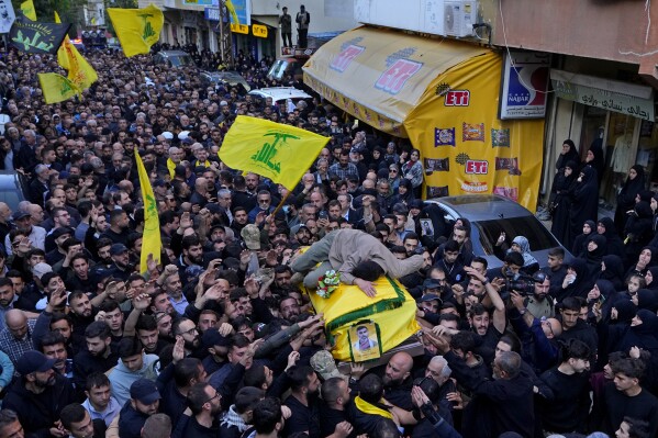 Ali, son of Abbas Mohammed Raad, the son of the head of Hezbollah's parliamentary bloc, Mohammed Raad, who was killed by an Israeli strike, lies on top of his father's coffin during his funeral procession in the southern town of Jbaa, Lebanon, Thursday, Nov. 23, 2023. The militant Hezbollah group fired more than 50 rockets at military posts in northern Israel on Thursday, a day after an Israeli airstrike on a home in southern Lebanon killed five of the group's senior fighters. (AP Photo/Bilal Hussein)
