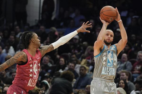 Golden State Warriors' Stephen Curry, right, shoots for three as Memphis Grizzlies' Ja Morant defends during the second half of the NBA All-Star basketball game, Sunday, Feb. 20, 2022, in Cleveland. (AP Photo/Charles Krupa)