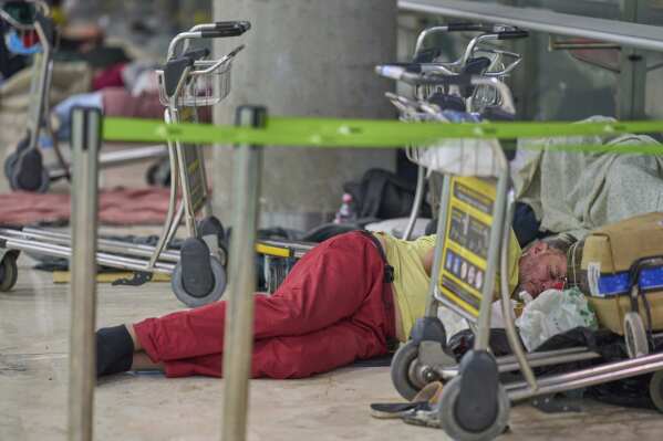 A person sleeps on the floor of Terminal 4 at Adolfo Suarez-Madrid Barajas Airport in Madrid, Spain, Thursday, May 15, 2025. (AP Photo/Manu Fernandez)