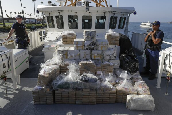 FILE - In this Aug. 29, 2019, file photo, members of the Coast Guard stand near seized cocaine in Los Angeles. The nation's drug addiction crisis has been morphing in a deadly new direction: more Americans struggling with meth and cocaine. Now the government will allow states to use federal money earmarked of the opioid crisis to help people addicted to those drugs as well. The change to a $1.5 billion opioid grants program was buried in a massive spending bill that Congress passed late in 2019. (AP Photo/Chris Carlson, file)