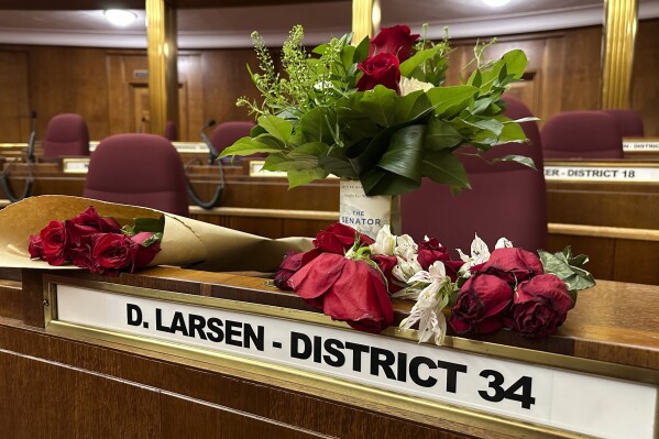 FILE - Flowers sit on the Senate desk of late North Dakota Sen. Doug Larsen, Oct. 6, 2023, inside the state Capitol in Bismarck, N.D. Larsen, his wife, Amy, and their two young children, 11-year-old Christian and 8-year-old Everett, died on Oct. 1, in a plane crash near Moab, Utah. Federal investigators say they found no evidence of a mechanical failure before the state senator's plane crashed in Utah, killing him, his wife and their two young children, according to a preliminary report released Thursday, Nov. 2, 2023, by the National Transportation Safety Board. (AP Photo/Jack Dura, File)