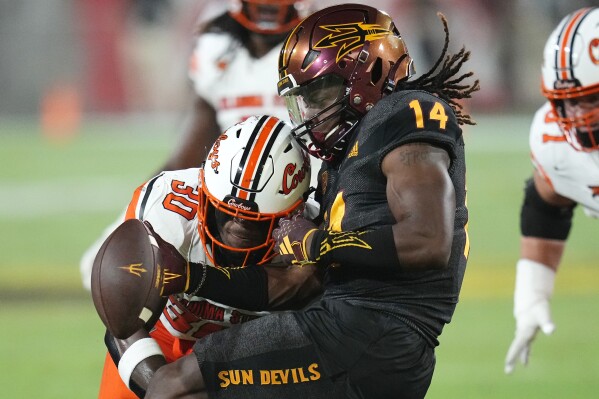 Oklahoma State linebacker Collin Oliver (30) forces a fumble as he knocks the ball loose from Arizona State running back Kyson Brown (14) during the first half of an NCAA college football game Saturday, Sept. 9, 2023, in Tempe, Ariz. Arizona State would recover the ball on the play. (AP Photo/Ross D. Franklin)