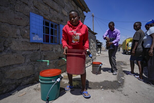 A woman fetches water with a bucket filter in Athi River, Machakos county, Kenya, Tuesday, Oct. 17, 2023. The devices are the size of a small water bottle and are fitted with a hose pipe onto a bucket. They can filter water from the river and nearby swamps into potable water that can be used by residents. (AP Photo/Brian Inganga)