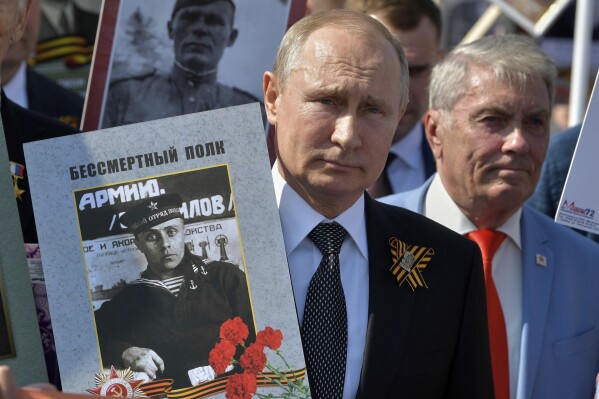 Russian President Vladimir Putin, center, holds a portrait of his father, also named Vladimir, as he walks with others carrying pictures of their relatives who fought in World War II, during celebrations in Red Square, in Moscow on May 9, 2019. (Alexei Druzhinin, Sputnik, Kremlin Pool Photo via AP, File)