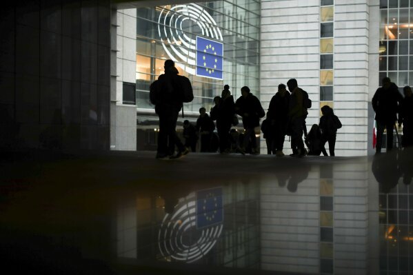 People walk past outside the European Parliament in Brussels, Friday, Jan. 24, 2020. The leaders of two of the European Union's main institutions on Friday signed the divorce agreement governing Britain's departure from the bloc next week, sealing the penultimate step in Brexit at a ceremony held without media access. (AP Photo/Francisco Seco)