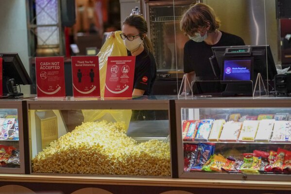 Concessions workers stock the bins with popcorn and other treats as the theatre opens for some of the first showings at the AMC theatre when it re-opened for the first time since shutting down at the start of the COVID-19 pandemic, Thursday, Aug. 20, 2020, in West Homestead, Pa. (AP Photo/Keith Srakocic)
