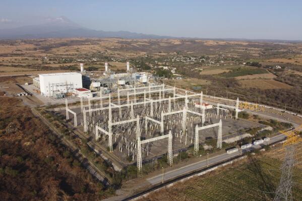FILE - A newly built power generation plant that is part of a mega-energy project is seen with the Popocatepetl Volcano in the background near Huexca, Morelos state, Mexico, on Feb. 22, 2020. The United States is putting pressure on Mexico over energy policies that Washington says unfairly favor Mexico's state-owned electricity and oil companies over American competitors and clean-energy suppliers. The U.S. is demanding talks to resolve the dispute, starting a process Wednesday, July 20, 2022, that could end in trade sanctions against Mexico. (AP Photo/Eduardo Verdugo, File)