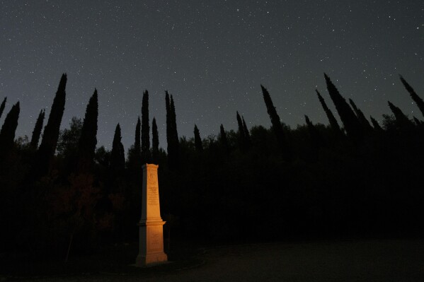The monument where the heart of French Baron Pierre de Coubertin is placed, is seen under the night sky in ancient Olympia, on Monday, April 8, 2024. Before he died in 1937 and was buried in Lausanne, Switzerland, Coubertin left special directions for his heart: It was to be removed and placed inside the monument erected in his honour ten years earlier just outside the ruins of ancient Olympia.(AP Photo/Petros Giannakouris)
