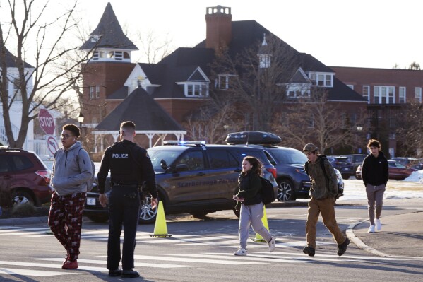 Students are released from school, under watch by local police, outside Thornton Academy following police activity in the area, Friday, Feb. 9, 2024, in Saco, Maine. Police in a Saco asked residents to shelter in place Friday afternoon while they searched for suspects after an exchange of gunfire and vehicle crash at a busy intersection spurred a brief citywide school lockdown. (AP Photo/Charles Krupa)