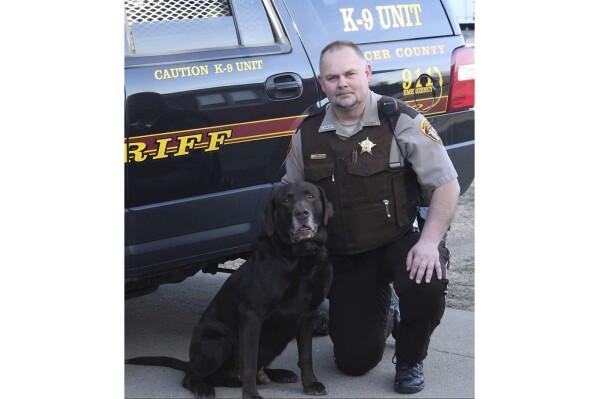 FILE - This undated photo provided by the Mercer County, N.D., Sheriff's Office shows Sheriff's Deputy Paul Martin with his retired K9 Goliath, who died in 2019. Martin, 53, died Wednesday, Dec. 6, 2023, in a crash involving Ian Cramer, the 42-year-old son of Republican U.S. Sen. Kevin Cramer of North Dakota. (Mercer County Sheriff's Office via AP)