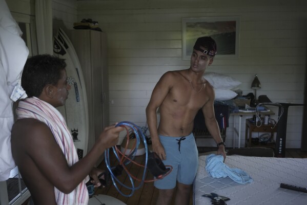 French Olympic athlete Kauli Vaast, right, and his brother Naiki, organize surf equipment in their bungalow in Vairao, Tahiti, French Polynesia, Sunday, Jan. 14, 2024. "Magical things happen here, you feel this energy and you must show respect," said Kauli Vaast. "It is so important to show respect in these types of places where you face mother nature." (AP Photo/Daniel Cole)