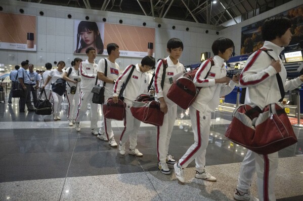 North Korean women wearing track suits with the North Korean flag and the words Taekwon-Do printed on the back walk to Chinese customs after checking in for a flight to Astana at the Capital Airport in Beijing, Friday, Aug. 18, 2023. A team of North Korean Taekwondo athletes are reportedly travelling via China to Astana, capital of Kazakhstan, to compete in a Taekwondo competition. (AP Photo/Ng Han Guan)