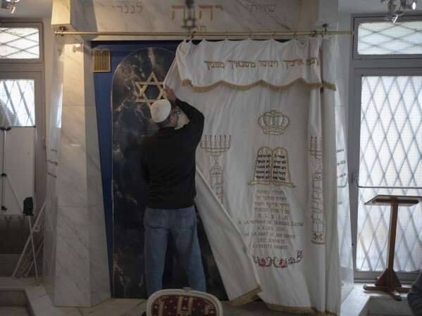 A Jewish congregant draws a curtain over the Torah ark at the Ohel Yaacov Synagogue in Marseille, southern France, Sunday, April 21, 2024. (AP Photo/Daniel Cole)