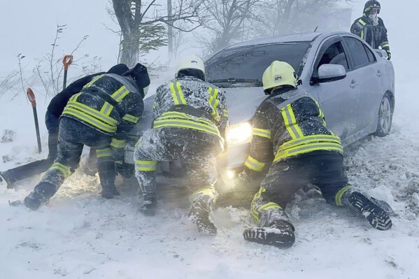 In this photo provided by the Ukrainian Emergency Service, Ukrainian Emergency workers try to push a car trapped in snow on the Odesa region highway, Ukraine, Monday, Nov. 27, 2023. Heavy snowfalls and storm has hit Ukraine on Monday leaving more than 2,000 towns and villages in war-torn country without power. (Ukrainian Emergency Service via AP Photo)