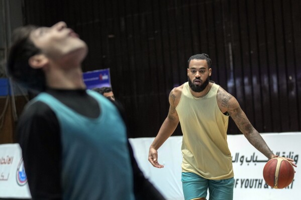 Isaac Banks, right, an American basketball player with the Hashed al-Shaabi - the Popular Mobilization Forces - in the Iraqi Basketball Super League, takes part in a team practice in Baghdad, Iraq, Thursday, March 21, 2024. U.S. players are in high demand on Iraqi basketball teams, even those whose owners have a tense relationship with Washington. (AP Photo/Hadi Mizban)