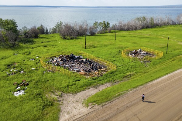 Yellow fencing surrounds two buildings destroyed by a May wildfire at Sturgeon Lake Cree First Nation, northwest of Edmonton, Alberta, on Tuesday, July 3, 2023. According to a tribe member, the two structures were the oldest on the reserve. (AP Photo/Noah Berger)