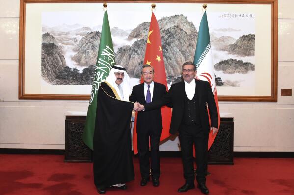 In this photo released by Xinhua News Agency, Ali Shamkhani, the secretary of Iran's Supreme National Security Council, at right, shakes hands with Saudi national security adviser Musaad bin Mohammed al-Aiban, at left, as Wang Yi, China's most senior diplomat, looks on, at center, for a photo during a closed meeting held in Beijing, Saturday, March 11, 2023. Iran and Saudi Arabia agreed Friday to reestablish diplomatic relations and reopen embassies after seven years of tensions. The major diplomatic breakthrough negotiated with China lowers the chance of armed conflict between the Mideast rivals, both directly and in proxy conflicts around the region. (Luo Xiaoguang/Xinhua via AP)
