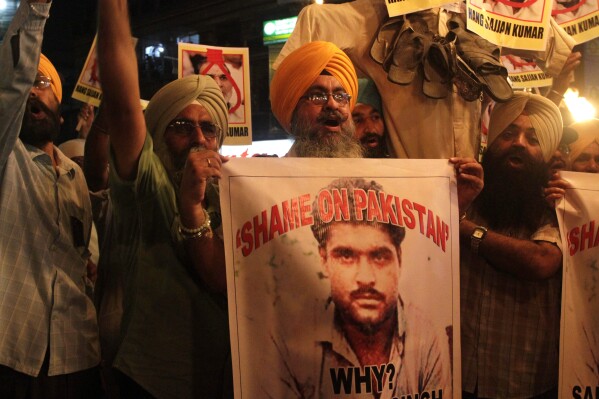 FILE - Indian Sikhs shout slogans against Pakistan as they display photographs of Sarabjit Singh, center, a convicted Indian spy who was on Pakistan's death row, died from a head injury after two inmates attacked him with a brick in a Lahore jail, during a protest in Kolkata, India, Thursday, May 2, 2013. A Pakistani police official says an investigation has begun after a man suspected in a fatal attack on an imprisoned Indian national more than a decade ago was shot dead at his home in the eastern city of Lahore. (AP Photo/Bikas Das, File)