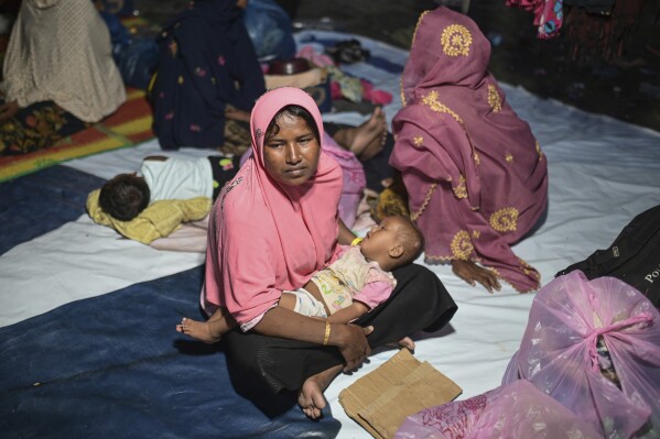 Ruzina, who goes by one name, holds her baby as she sits in a tent at a camp set up near the beach where she and other ethnic Rohingya people were killed on Dec. 10 in Pidi, Aceh province, Indonesia. Landed on Friday, December.  15, 2023. (AP Photo/Reza Saifullah)