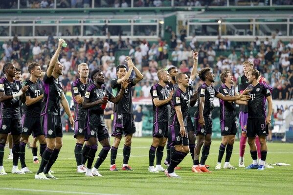 Bayern's players, including Harry Kane, right, celebrate their victory after the German Bundesliga soccer match between Werder Bremen and Bayern Munich, at the Weserstadion in Bremen, Germany, Friday, Aug. 18, 2023. (Axel Heimken/dpa via AP)