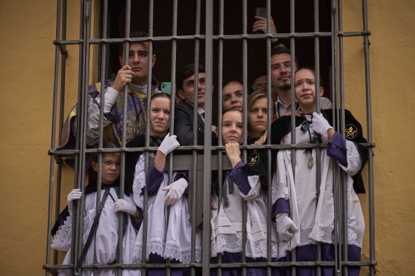 Altar servers crowd a window to watch a Christ of the San Bernardo brotherhood Holy Week procession, in Seville, Spain, April 16, 2025. (AP Photo/Emilio Morenatti)