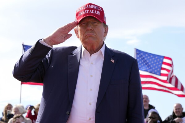 FILE - Republican presidential candidate former President Donald Trump salutes at a campaign rally March 16, 2024, in Vandalia, Ohio. Trump is making the Jan. 6, 2021 attack on the Capitol a cornerstone of his bid to return to the White House. Trump opened his first rally as the presumed Republican Party presidential nominee standing in salute with a recorded chorus of Jan. 6 prisoners singing the national anthem.(AP Photo/Jeff Dean)