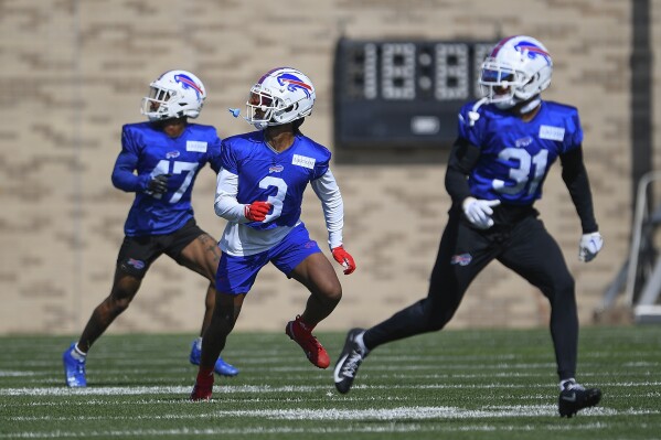 Buffalo Bills safety Damar Hamlin, center, runs a drill with cornerback Christian Benford, left, and safety Dean Marlowe during practice at the NFL football team's training camp in Pittsford, N.Y., Sunday, July 30, 2023. (AP Photo/Adrian Kraus)