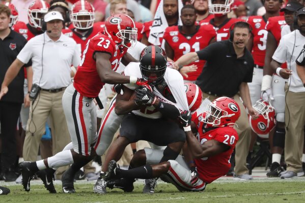 Arkansas State wide receiver Kirk Merritt (13) is dragged down by Georgia defensive backs Mark Webb (23) and J.R. Reed (20) In the first half of an NCAA college football game Saturday, Sept. 14, 2019, in Athens, Ga. (AP Photo/John Bazemore)