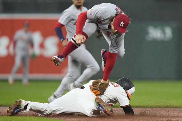 Cedric Mullins, abajo, de los Orioles de Bltimore, se roba segunda base frente a Brendan Donovan, brincando, de los Cardenales de San Luis, durante la segunda entrada del juego de béisbol de Grandes Ligas, el miércoles 28 de mayo de 2025, en Baltimore. (AP Foto/Stephanie Scarbrough)