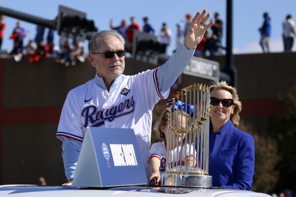 Riding with the Commissioner's Trophy, Texas Rangers manager Bruce Bochy, left, waves to fans as his wife Kim Seib, right, looks on during a parade for the baseball World Series-champion team in Arlington, Texas, Friday, Nov. 3, 2023. (Tom Fox/The Dallas Morning News via AP, Pool)