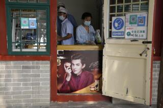 Food vendors work behind an ice cream fridge with an advertisement featuring Chinese-Canadian pop star Kris Wu in Beijing on Tuesday, Aug. 3, 2021. Wu was arrested Monday, Aug. 16, 2021 on suspicion of rape in a high-profile case that followed accusations the singer had sex with a 17-year-old while she was drunk and lured young women into sexual relationships. (AP Photo/Ng Han Guan)