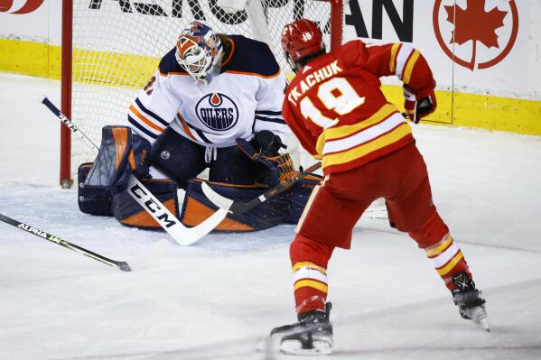 Edmonton Oilers goalie Mike Smith, left, lets in a goal from Calgary Flames' Matthew Tkachuk during the second period of an NHL hockey game Saturday, March 26, 2022, in Calgary, Alberta. (Jeff McIntosh/The Canadian Press via AP)