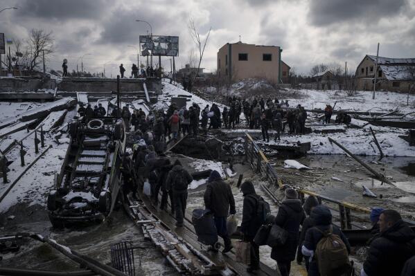 FILE - Ukrainians cross an improvised path under a destroyed bridge while fleeing Irpin, in the outskirts of Kyiv, Ukraine, Tuesday, March 8, 2022. As milestones go, the first anniversary of Russia's invasion of Ukraine is both grim and vexing. It marks a full year of killing, destruction, loss and pain felt even beyond the borders of Russia and Ukraine. (AP Photo/Felipe Dana, File)