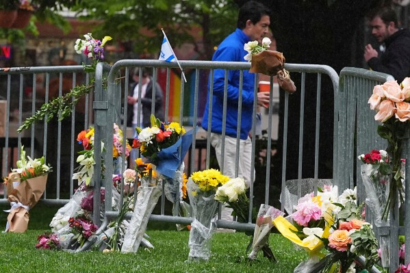 Bouquets of flowers stand along a makeshift memorial for victims of an attack outside of the Boulder County, Colo., courthouse as a light rain falls Tuesday, June 3, 2025, in Boulder, Colo. (AP Photo/David Zalubowski)