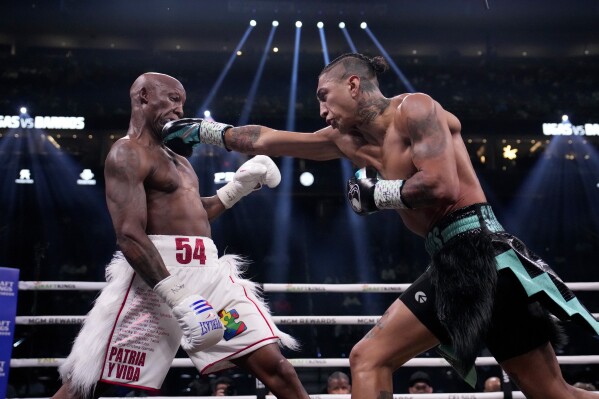 Yordenis Ugas, left, fights Mario Barrios in a welterweight boxing match Saturday, Sept. 30, 2023, in Las Vegas. (AP Photo/John Locher)