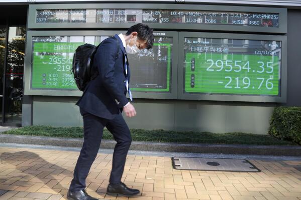 A man walks by an electronic stock board of a securities firm in Tokyo, Wednesday, Nov. 24, 2021. Asian shares fell Wednesday, as worries about inflation set off expectations the U.S. Federal Reserve might raise interest rates.(AP Photo/Koji Sasahara)