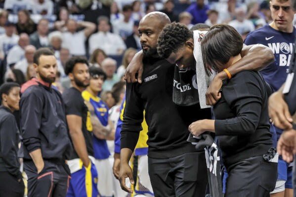 Minnesota Timberwolves guard Anthony Edwards (5) is helped off the court after sustaining an injury during the first half of Game 2 of an NBA basketball second-round playoff series against the Golden State Warriors, Thursday, May 8, 2025, in Minneapolis. (Carlos Avila Gonzalez/San Francisco Chronicle via AP)