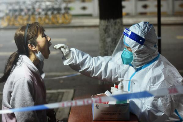 A medical worker takes swab sample from a resident for COVID-19 test in Hangzhou in eastern China's Zhejiang province Tuesday, March 15, 2022. China's new COVID-19 cases Tuesday more than doubled from the previous day as it faces by far its biggest outbreak since the early days of the pandemic. (Chinatopix via AP)