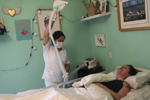 FILE - A nurse readies a portable medical ventilator for Ana Estrada, a Peruvian psychologist, to receive oxygen in her bedroom, Lima, Peru, Dec. 18, 2019. Estrada, who suffered from an incurable disease and was authorized in 2022 by Peru's Supreme Court to receive euthanasia, has died, her lawyer said Monday, April 22, 2024. (AP Photo/Martin Mejia, File)