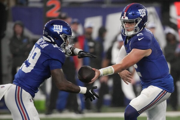 New York Giants quarterback Drew Lock (2) hands off the ball to New York Giants running back Tyrone Tracy Jr. (29) during the first quarter of an NFL football game, Thursday, Aug. 8, 2024, in East Rutherford, N.J. (AP Photo/Pamela Smith)