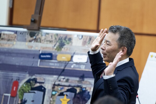 State assistant attorneys general Kent Liu demonstrates how Manny Ellis raised his hand as he presents his opening statement during the trial of Tacoma Police Officers Christopher Burbank, Matthew Collins and Timothy Rankine in the killing of Manny Ellis, Tuesday, Oct. 3, 2023, at Pierce County Superior Court, Tacoma, Wash. (Brian Hayes/The News Tribune via AP, Pool)