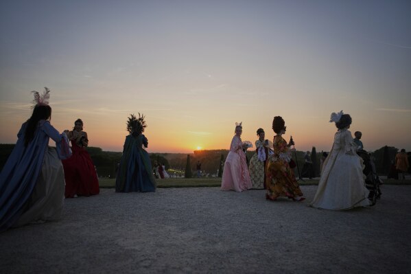 Costumed guests arrive in the gardens of the Versailles castle before the Great Masked Ball, in Versailles, outside Paris, Saturday, June 21, 2025. (AP Photo/Christophe Ena)