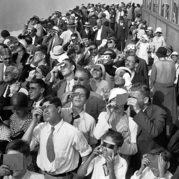 FILE - Eclipse watchers squint through protective filters as they view an eclipse of the sun from the top deck of New York's Empire State Building in New York on Wednesday, Aug. 31, 1932. Full solar eclipses occur every year or two or three, often in the middle of nowhere like the South Pacific or Antarctic. (AP Photo/File, File)