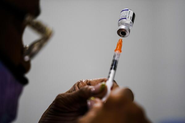 FILE - A syringe is prepared with the Pfizer COVID-19 vaccine at a vaccination clinic at the Keystone First Wellness Center in Chester, Pa., Dec. 15, 2021. The White House is planning for what it calls “dire” contingencies that could include rationing supplies of vaccines and treatments this fall if Congress doesn’t approve more money for fighting COVID-19. Biden administration officials have been warning for weeks that the country has spent nearly all the money approved for COVID-19 response. (AP Photo/Matt Rourke, File)